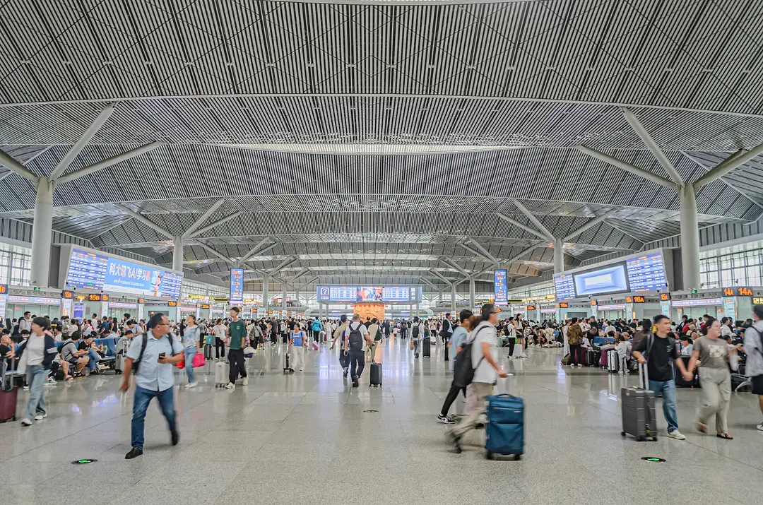 Travelers with suitcases crossing the large departure hall of Xi'an North high-speed railway station