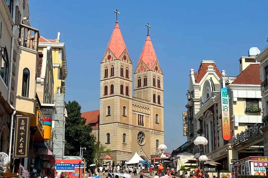 The twin spires of St. Michael's Cathedral at the top of a street of shops in Qingdao's old town