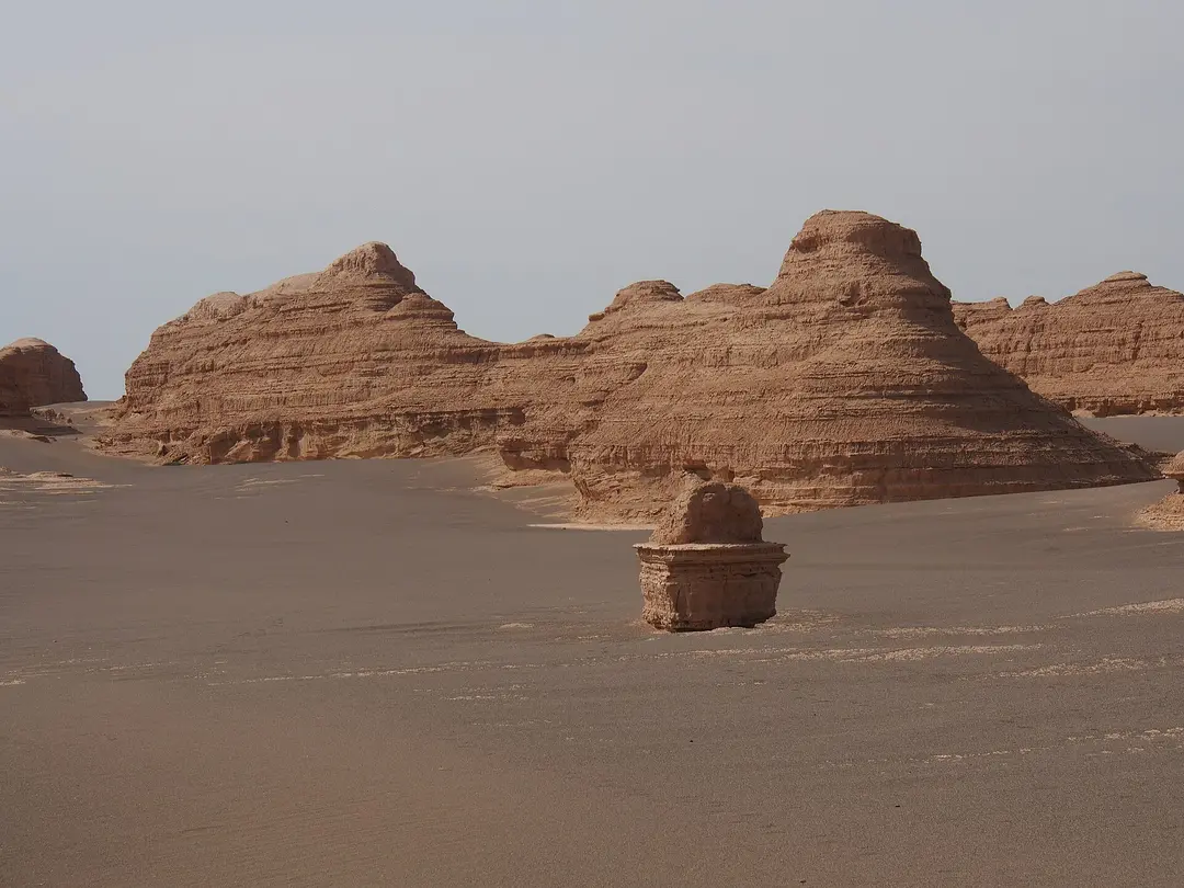 Wind-carved clay ridges rising from flat grey gravel desert in the Dunhuang Yadan geopark