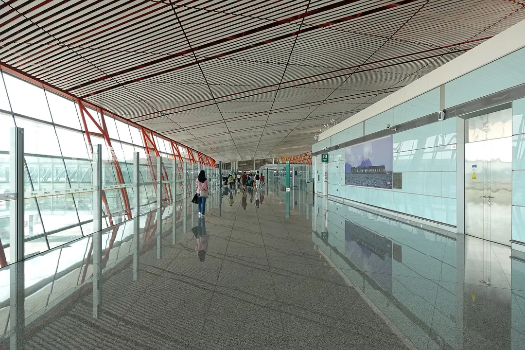 Passengers walking along the glass-walled international arrivals corridor of Beijing Capital Airport Terminal 3