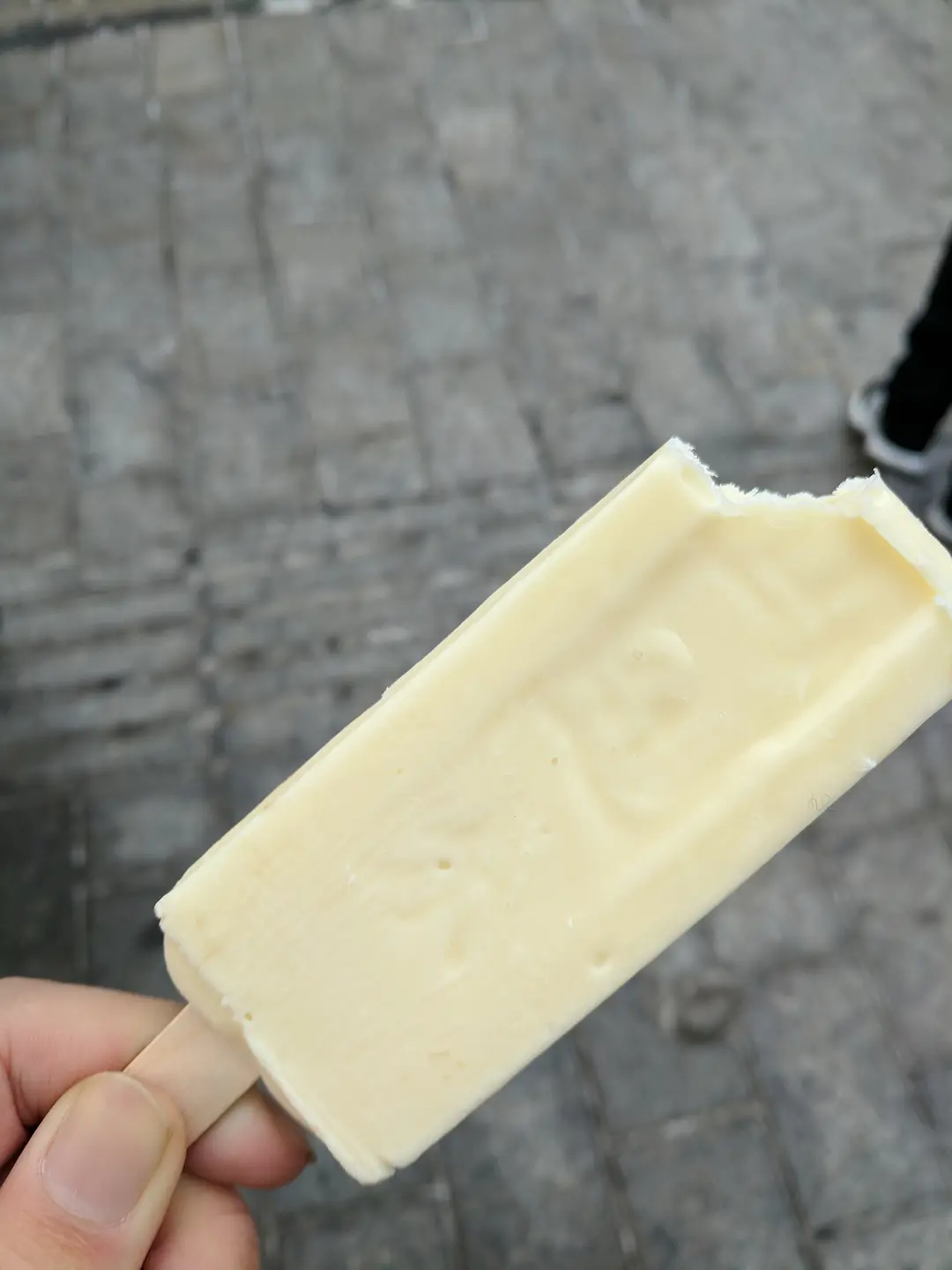 Hand holding a pale vanilla ice pop on Central Street