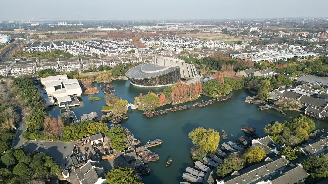 Aerial view of Wuzhen's waterways, tiled roofs and a modern arts centre beside a lake in winter
