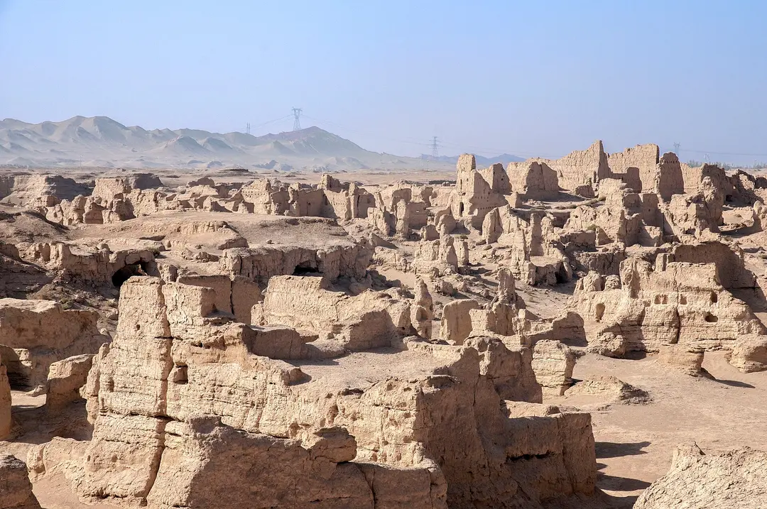 Eroded mud-brick walls of the Jiaohe ruins near Turpan stretching toward bare desert hills