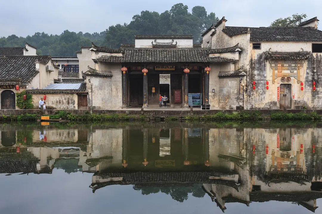 White-walled Huizhou houses with dark tiled roofs reflected in the still water of Moon Pond, Hongcun