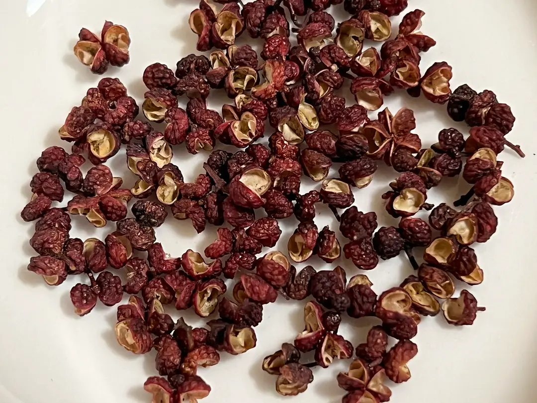 Dried red Sichuan peppercorn husks scattered on a white surface