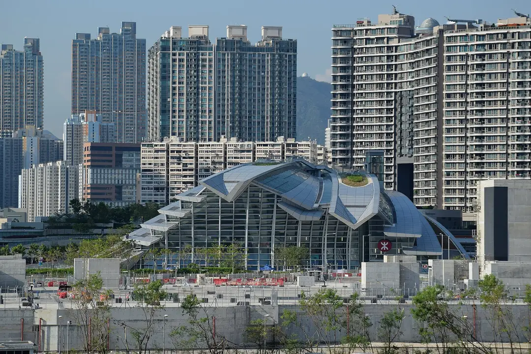 Curved glass and steel roof of Hong Kong West Kowloon high-speed rail station below residential towers