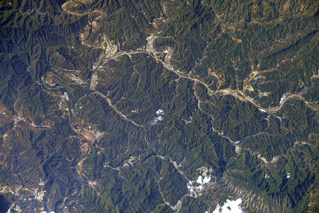 Forested mountain ridges, river valleys, roads and villages in northern China photographed from the International Space Station