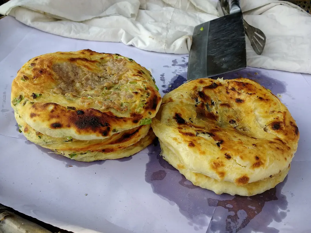 Two round Xizhou baba flatbreads, golden and charred from baking