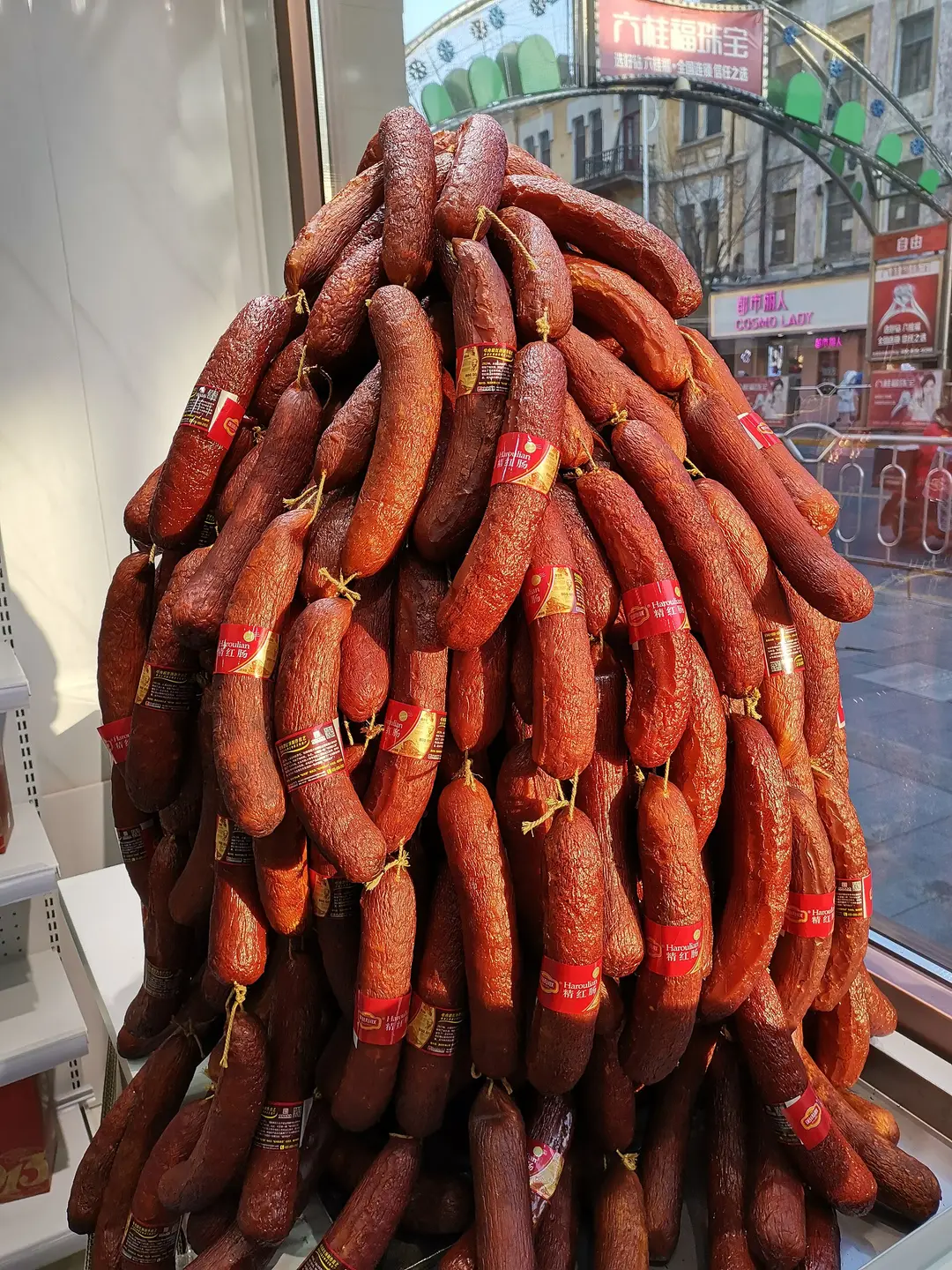 Bunches of reddish cured sausages hanging in a Harbin shop
