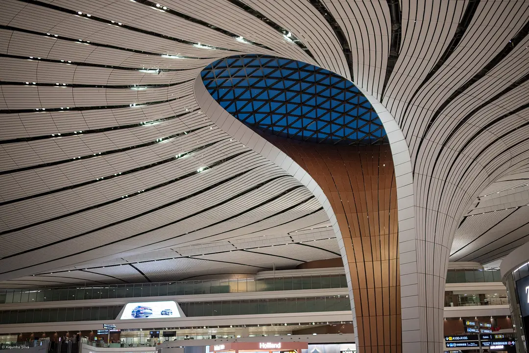 The curved white ceiling and a skylight column above the departures level of Beijing Daxing International Airport