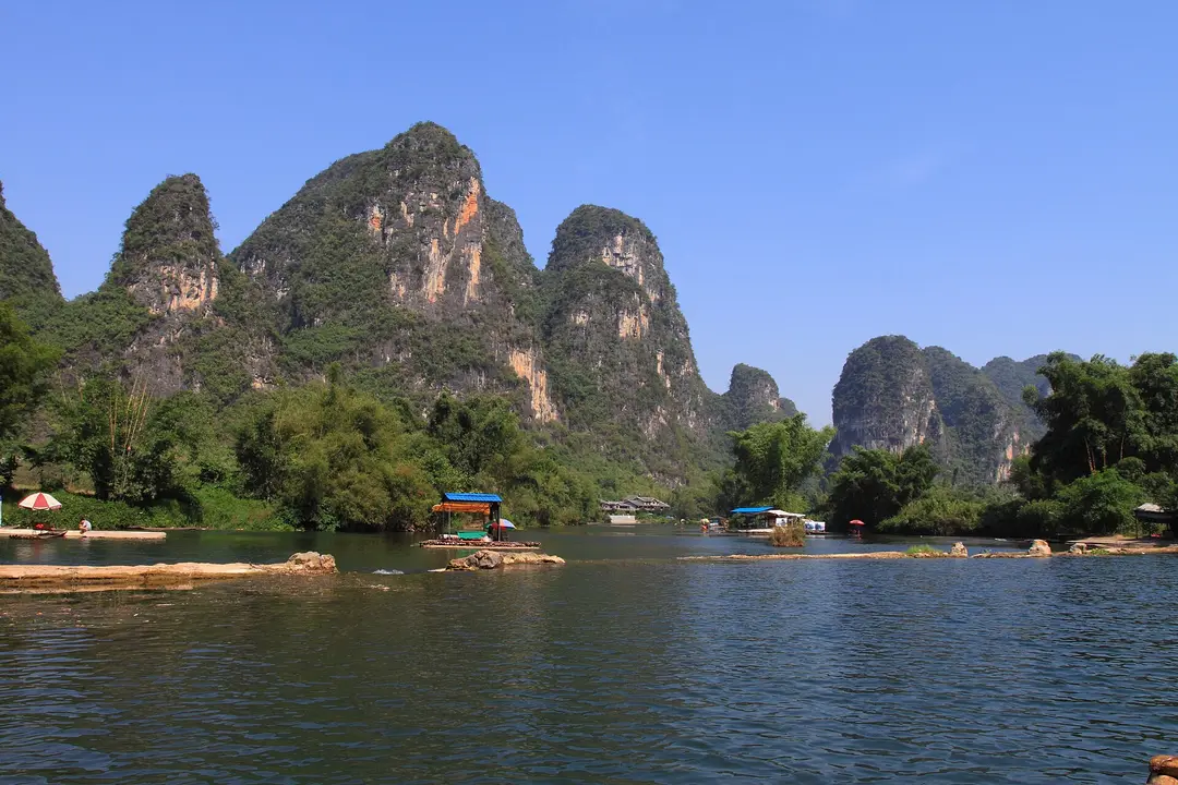 A bamboo raft on the Yulong River near Yangshuo, with karst peaks under a clear blue sky