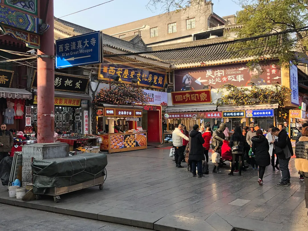 A paved street in the Muslim Quarter with food shops, shop signs and people walking