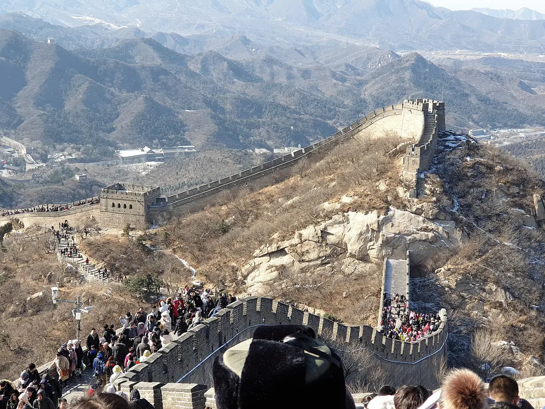 Visitors walking the Great Wall at Badaling on a clear winter day, the wall climbing over the hills