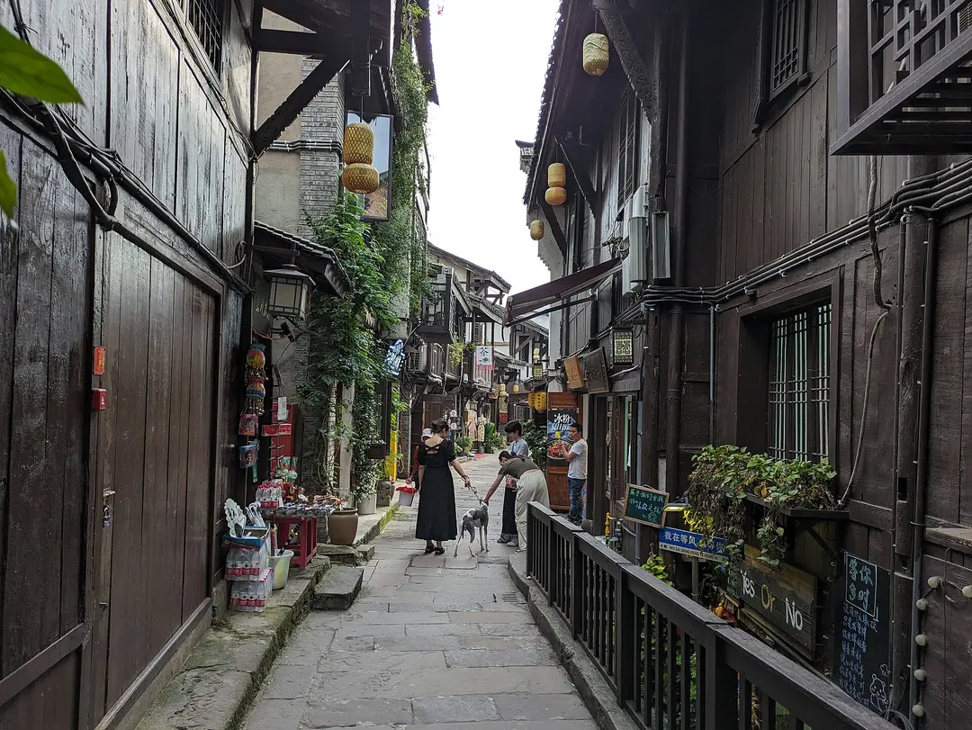 A narrow flagstone lane between dark wooden houses hung with lanterns in Ciqikou old town
