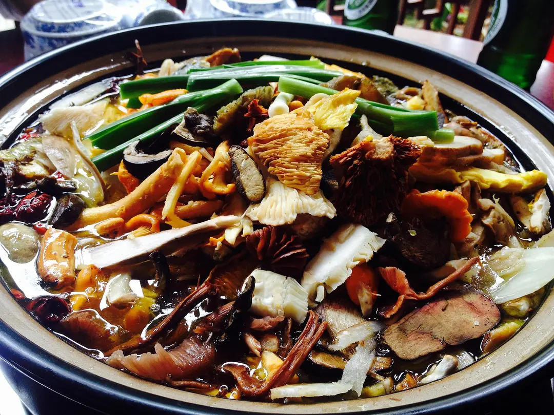 A hotpot heaped with many kinds of wild mushrooms and green beans
