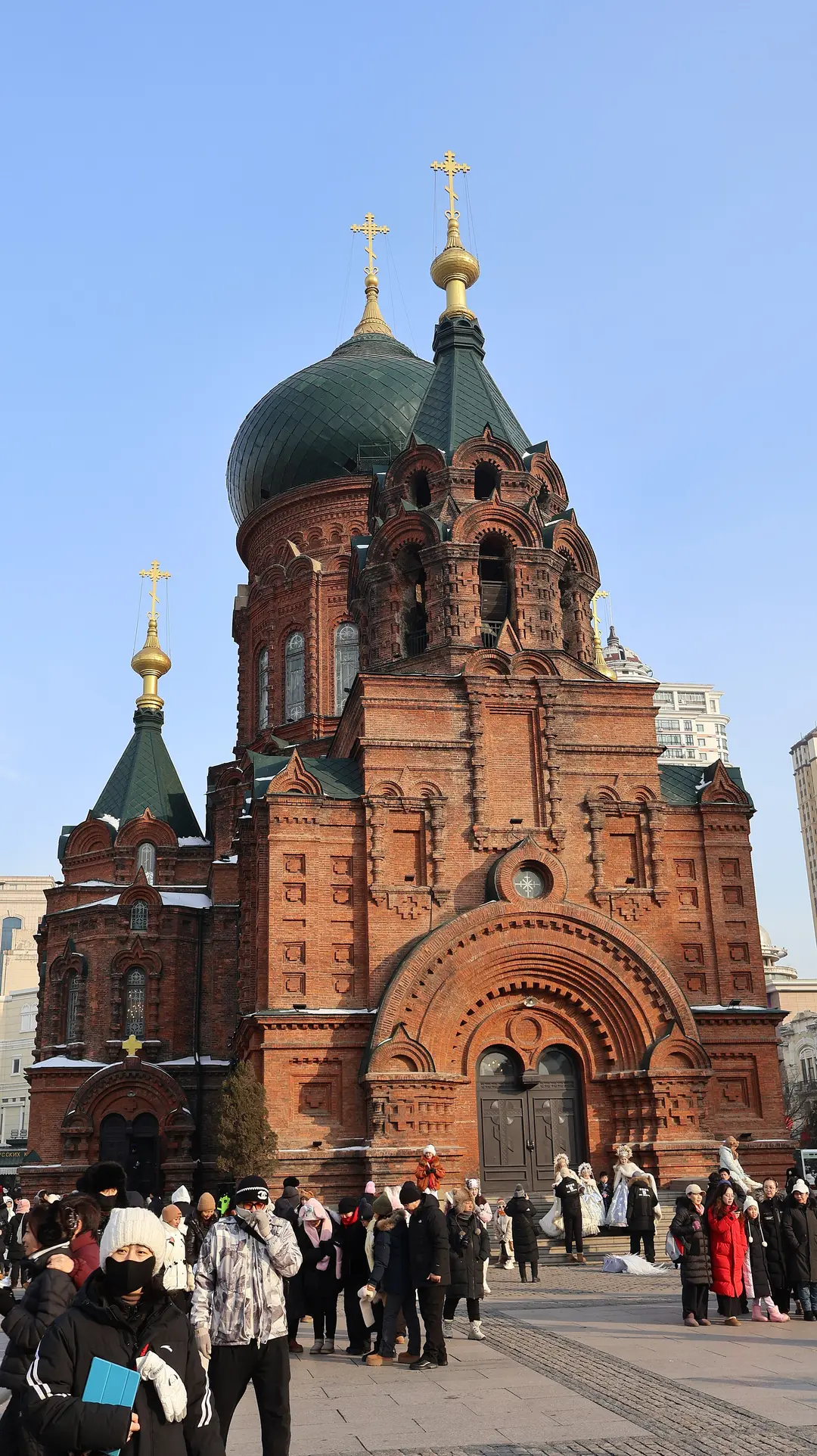The red-brick St Sophia Cathedral with its green onion dome, and visitors in winter coats on the square