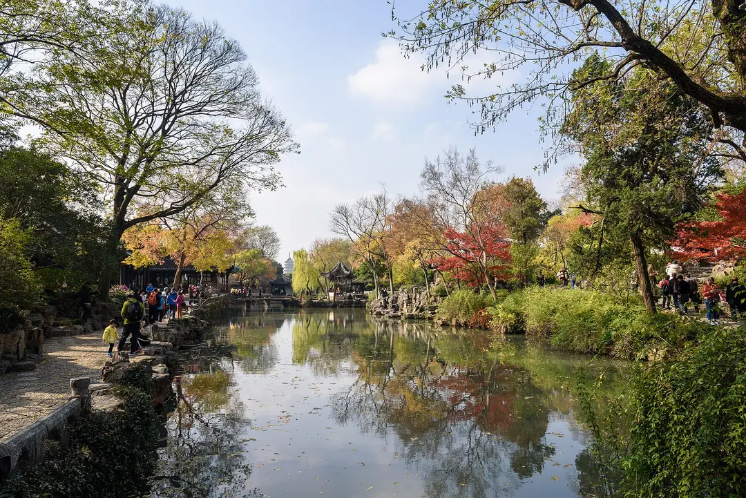 A still pond in the Humble Administrator's Garden, lined with autumn trees and a small pavilion