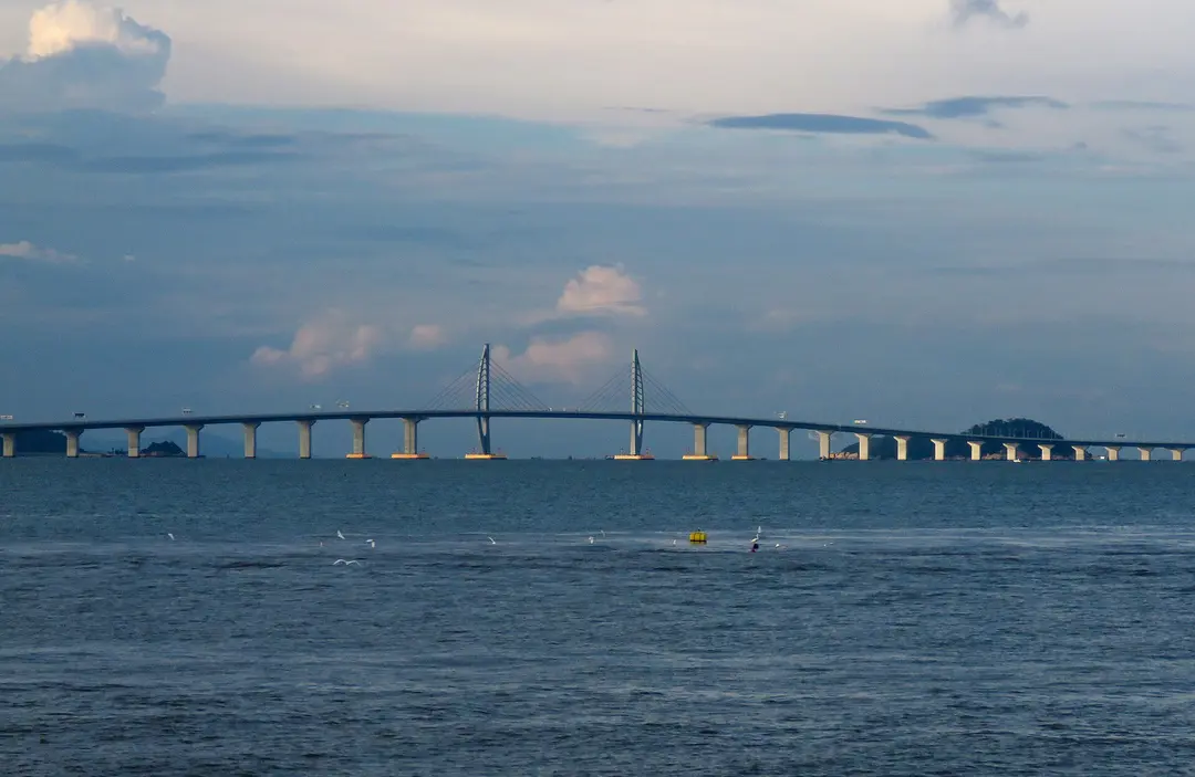 The western section of the Hong Kong–Zhuhai–Macao Bridge stretching low across the sea under a cloudy sky