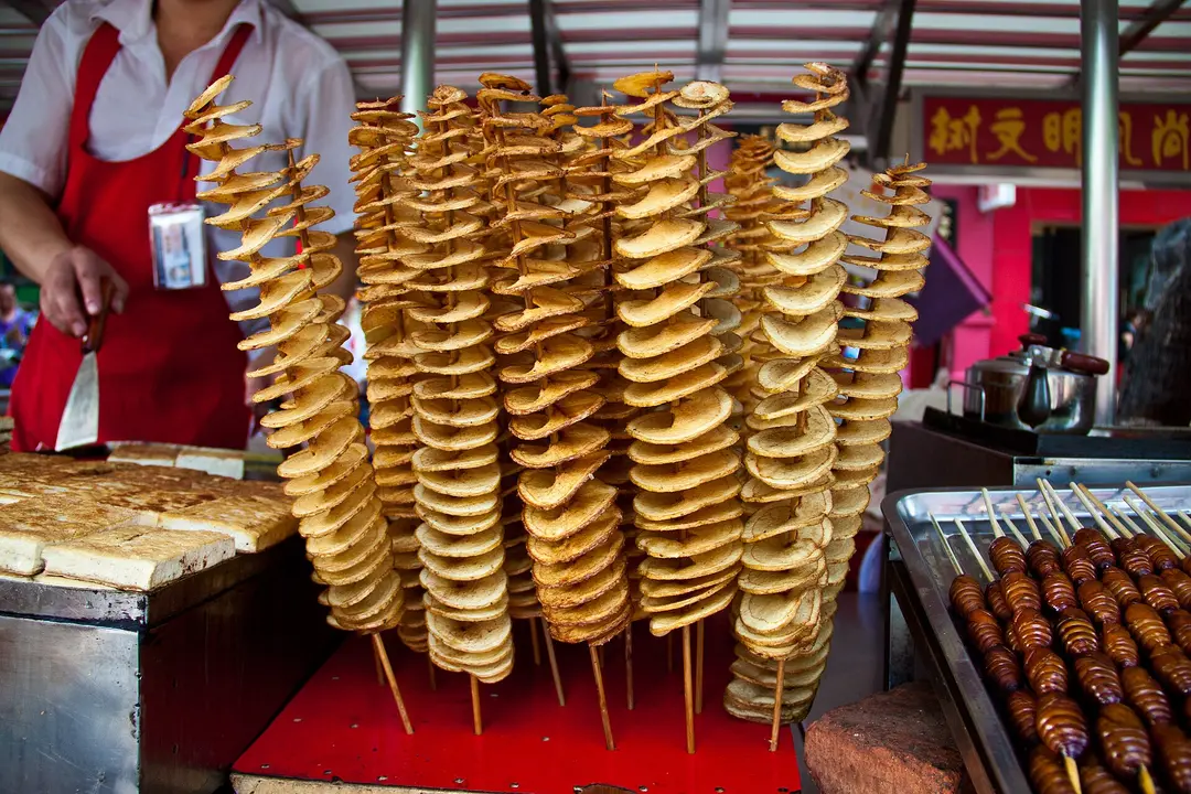 Spiral-cut fried potatoes on sticks and skewered snacks at a Wangfujing food stall, Beijing