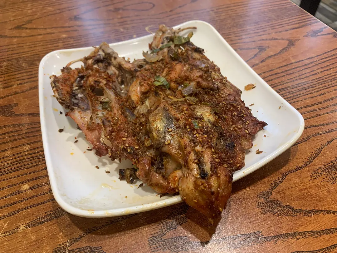 Grilled chicken frame dusted with spices, sesame and spring onion on a white plate