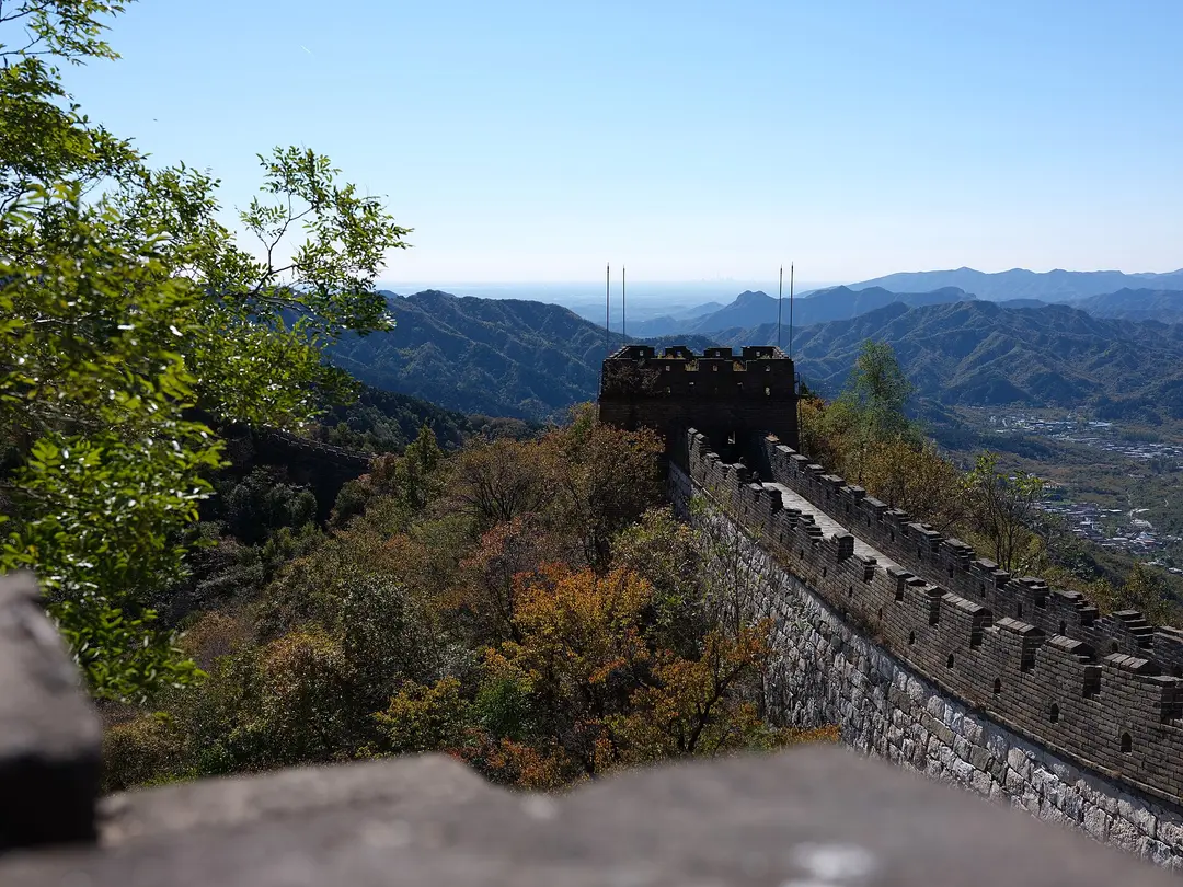 A Great Wall watchtower above hills turning orange and brown under a clear blue October sky