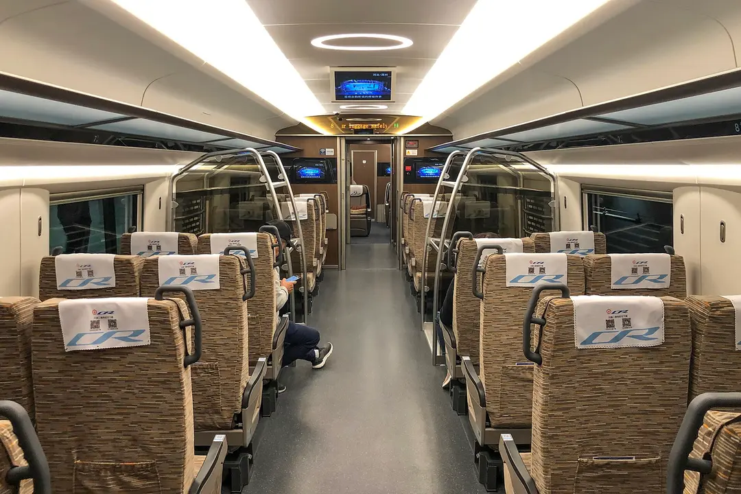 The quiet first-class carriage of a Fuxing high-speed train, with wide seats and soft lighting