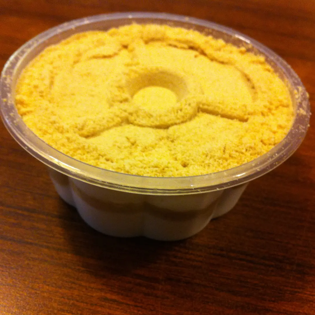 A cup of serradura topped with a thick layer of pale biscuit crumbs