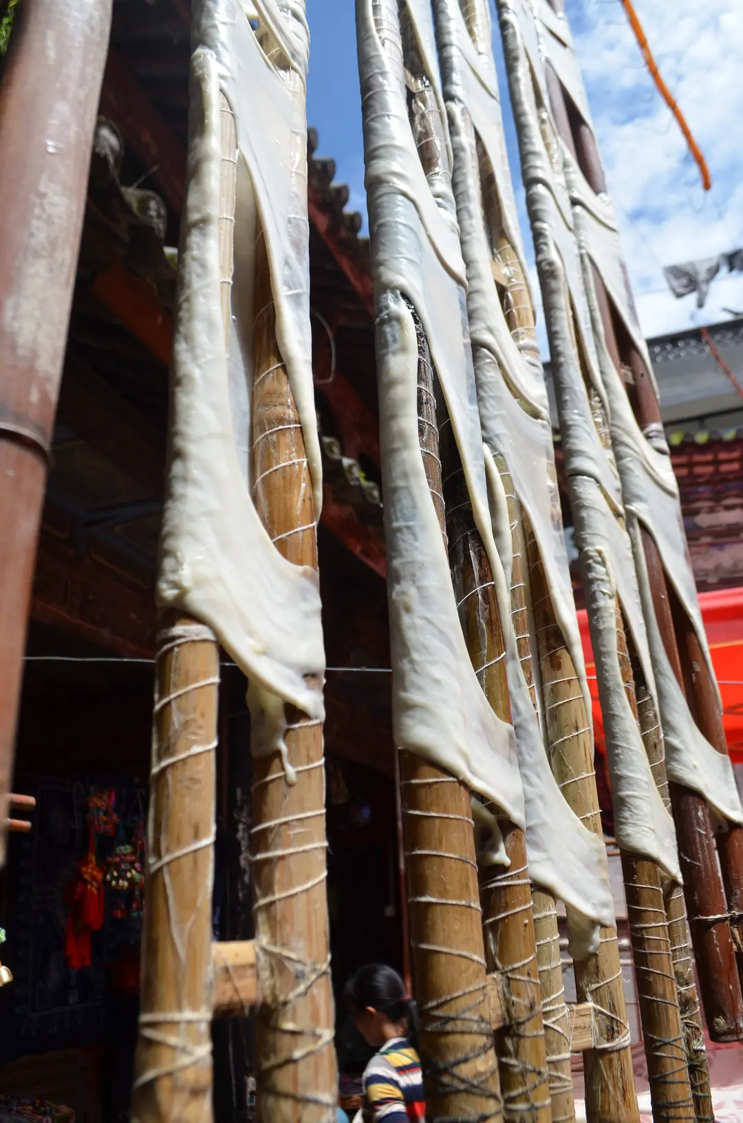 Sheets of rushan cheese stretched to dry on bamboo poles in Xizhou