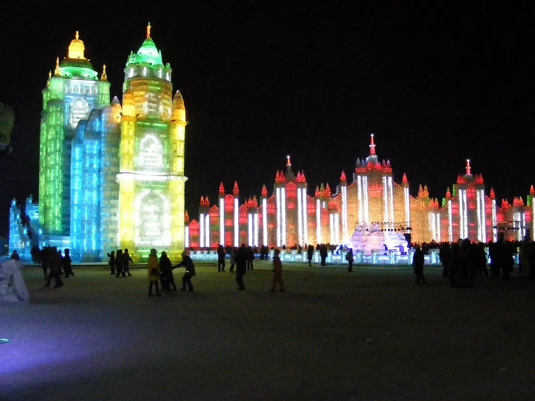 Ice palaces lit green, yellow and red at night at Harbin Ice and Snow World
