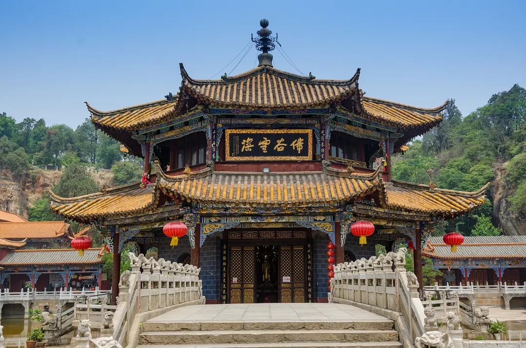 A two-tiered pavilion hung with red lanterns at Yuantong Temple, reached by a stone bridge