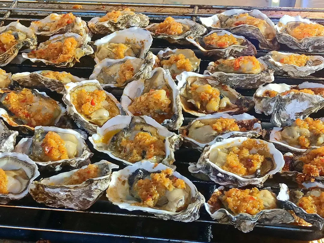 Oysters in the half shell grilling under garlic and chili on a rack