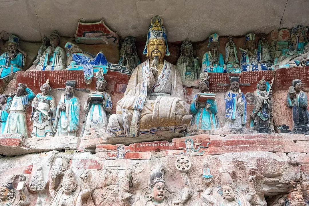 Painted stone figures carved into a cliff at Baodingshan, Dazu, with a seated gilded figure at the center