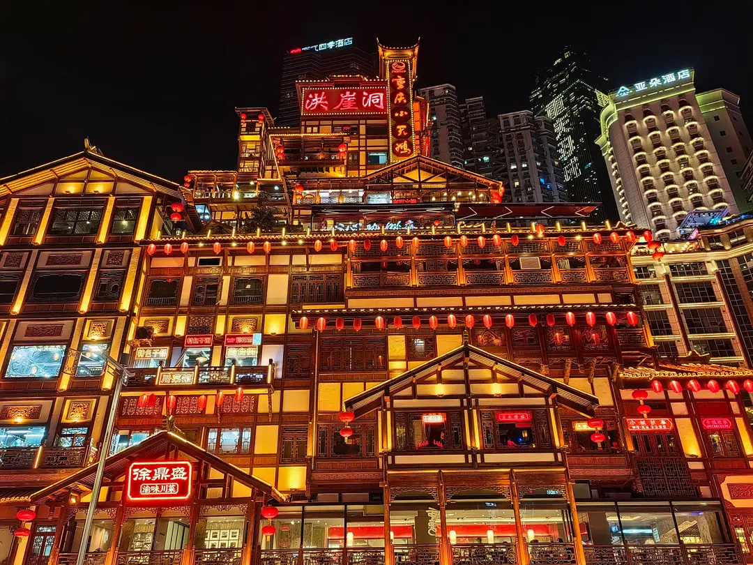 Hongyadong in Chongqing at night, its stacked wooden buildings lit gold and hung with red lanterns