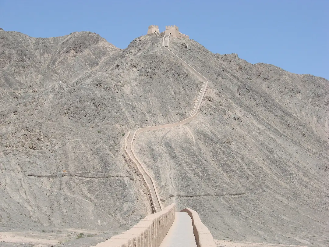 The Overhanging Great Wall near Jiayuguan climbing a bare grey desert ridge to a watchtower in Gansu