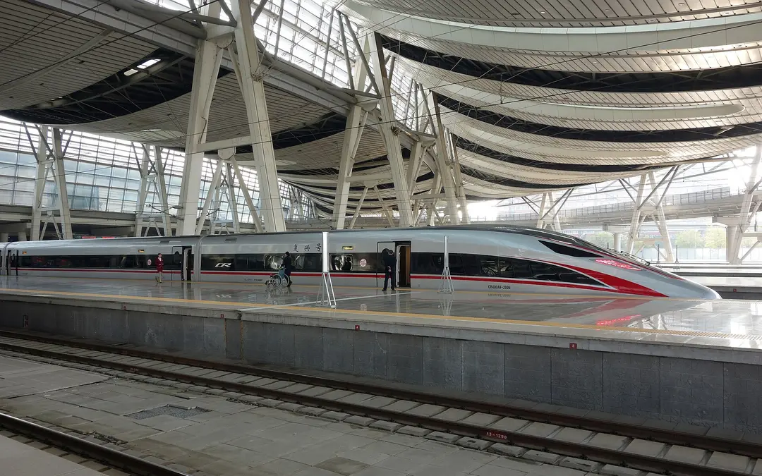 Silver and red Fuxing CR400AF train at a platform under Beijing South station's curved roof