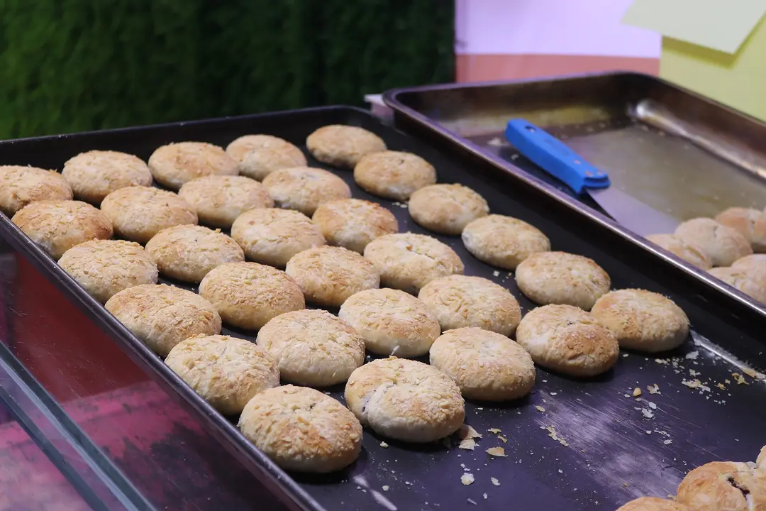 Rows of rose flower cakes on baking trays in Dali Old Town
