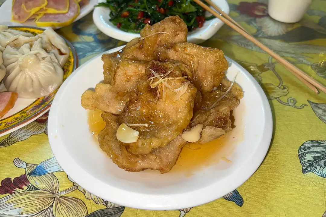 Crisp battered pork slices in a glossy sweet-and-sour sauce on a plate