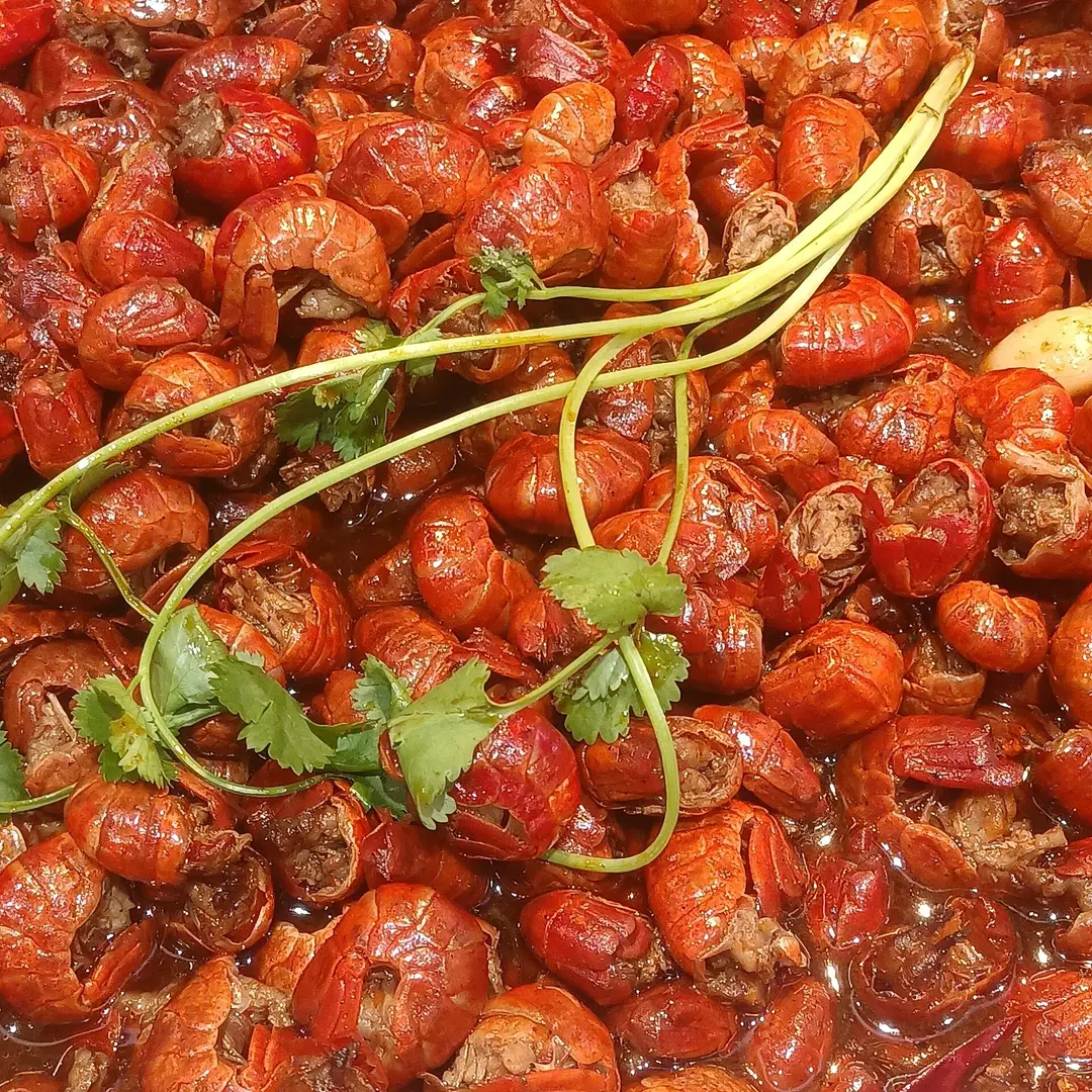 A heap of red spicy crayfish topped with fresh coriander