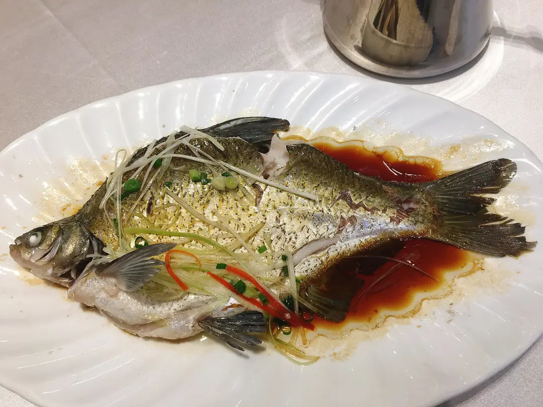 A whole steamed bream in soy sauce topped with shredded ginger, scallion and red chili