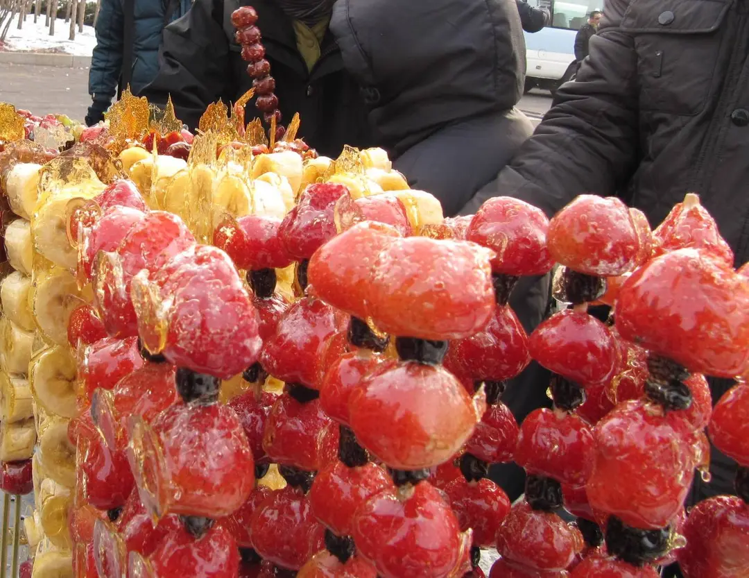 Skewers of red fruit in a shiny hard sugar coating at a street stall