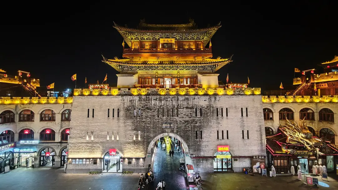 Lijing Gate lit up at night, a gate tower on a stone wall with an arched passage below