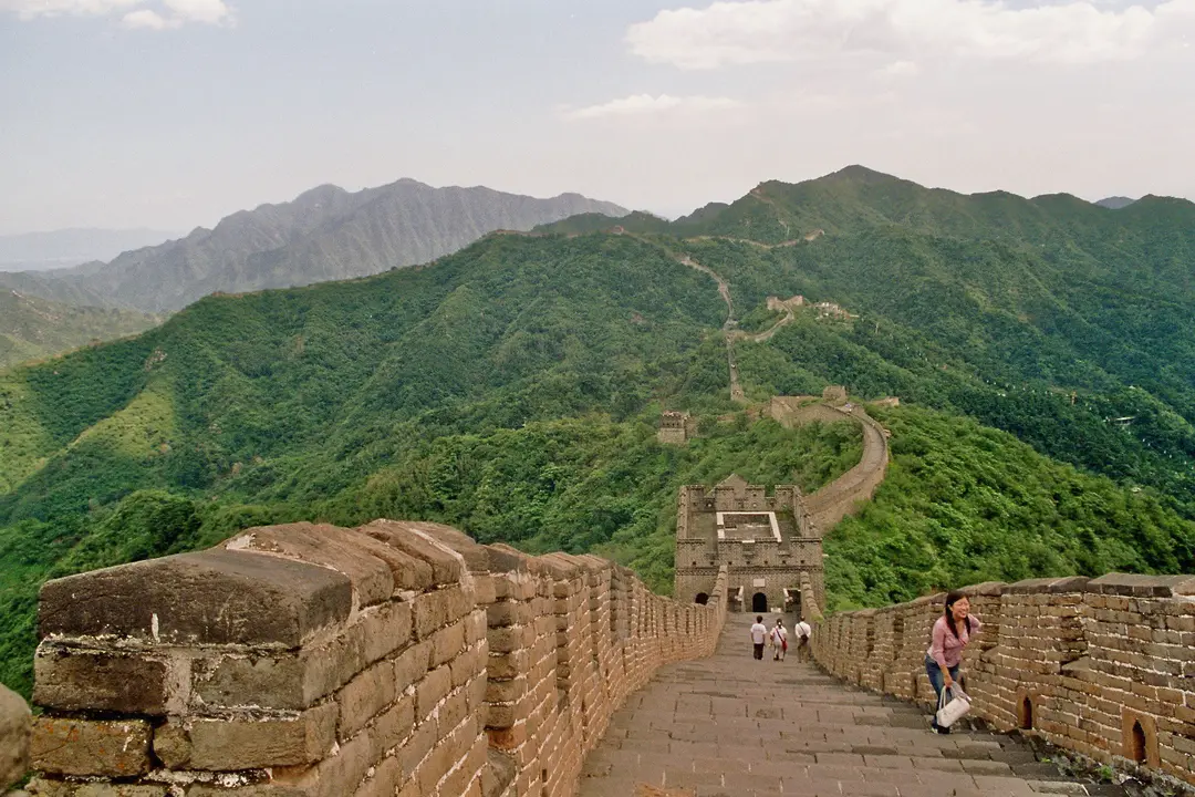 The Great Wall at Mutianyu crossing green mountain ridges, with a few walkers on the wall