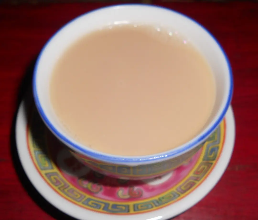 A china cup of pale, milky butter tea on a patterned saucer