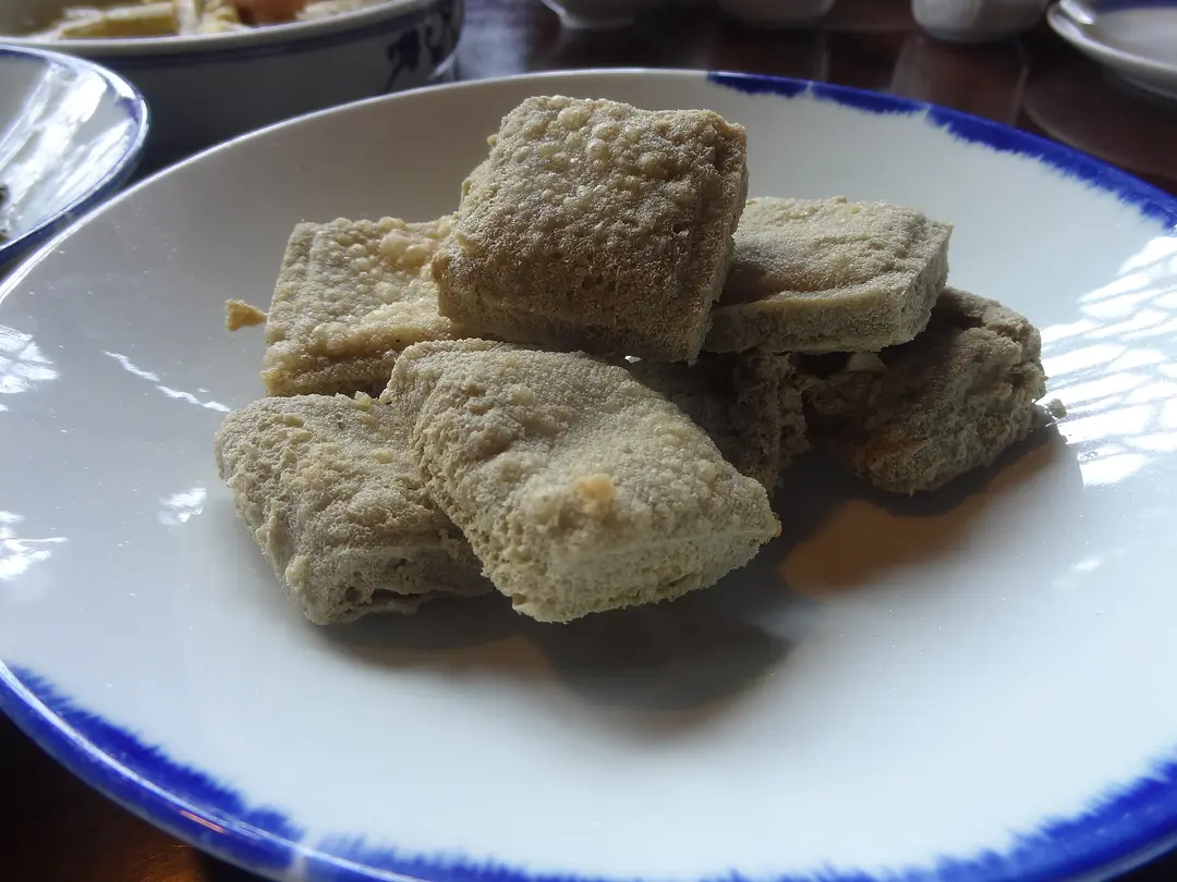 Golden fried cubes of stinky tofu on a white plate at a restaurant in Wuzhen