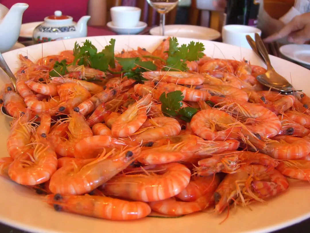 A platter of whole boiled prawns garnished with coriander on a restaurant table
